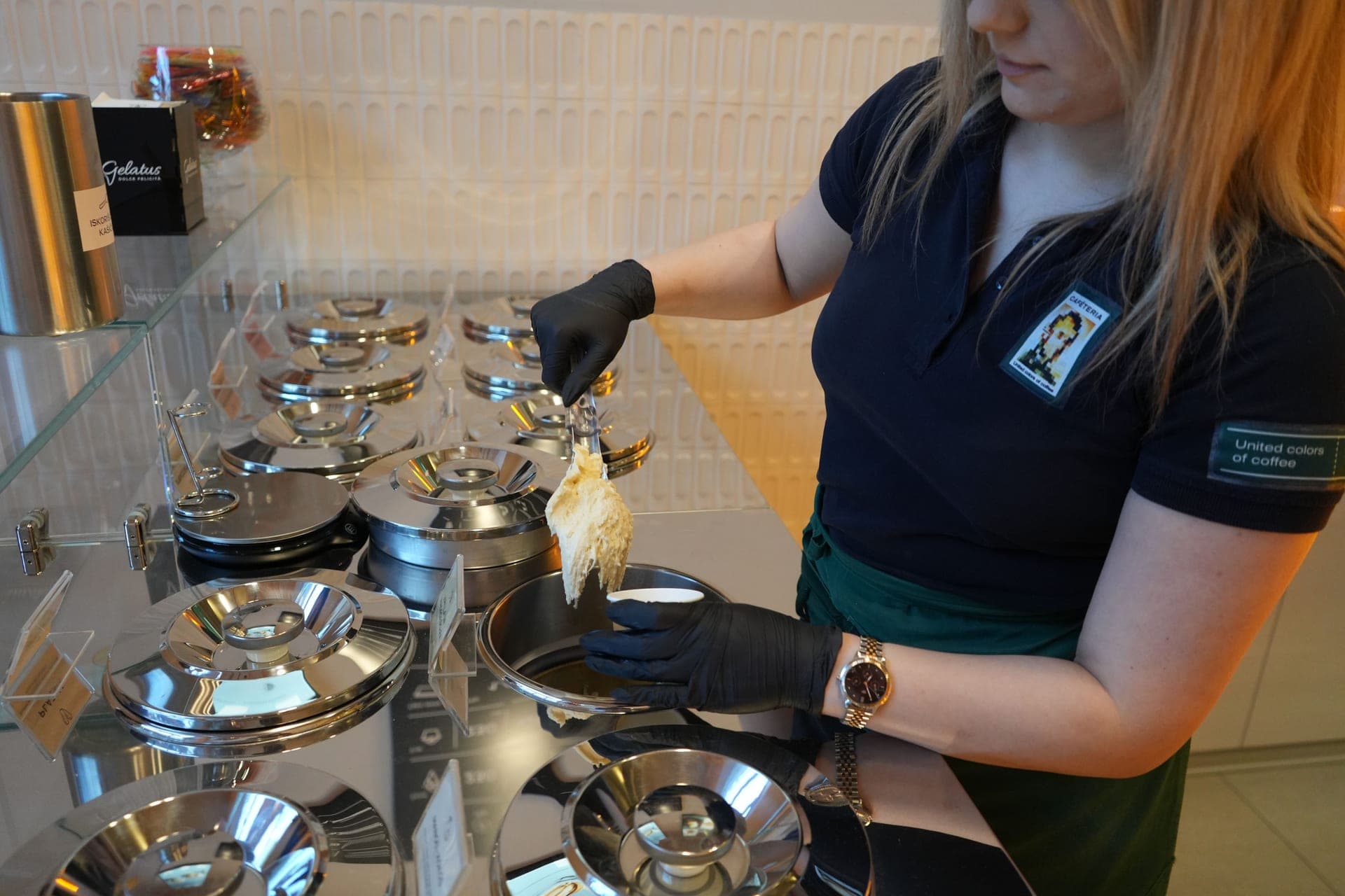 Gelato being served from a stainless steel counter in a cafe